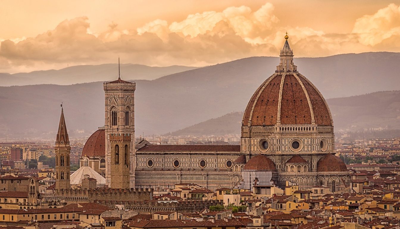 Brunelleschi's dome and Giotto's campanile glowing at sunset above Florence's terracotta rooftops and Tuscan hills