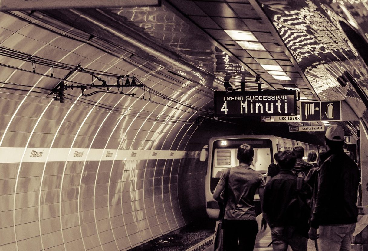 Passengers waiting on a curved Rome metro platform as a train arrives, with a sign reading next train in 4 minutes