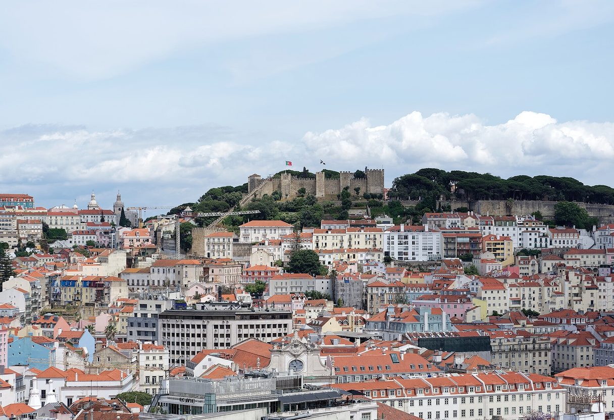 Castelo de São Jorge's crenellated walls and towers crowning its green hilltop above Lisbon's dense rooftops