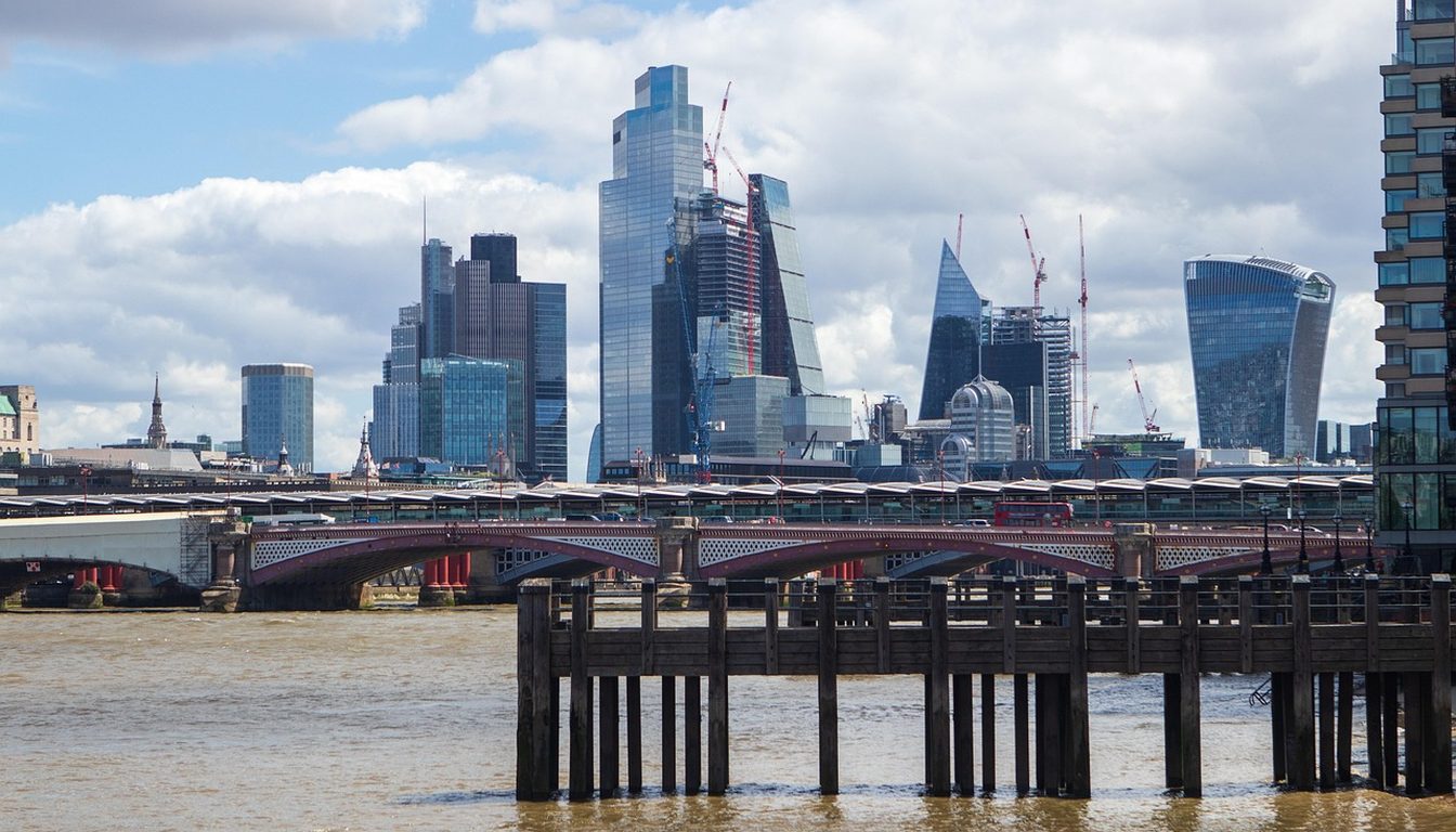 City of London skyscrapers rising behind Blackfriars railway bridge and old wooden pier posts in the Thames
