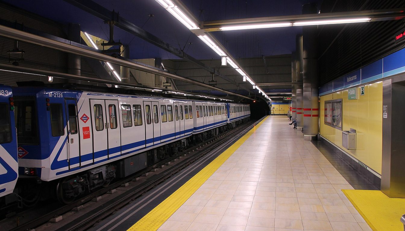 White and blue Madrid Metro train stopped at the underground Valdecarros platform with yellow walls