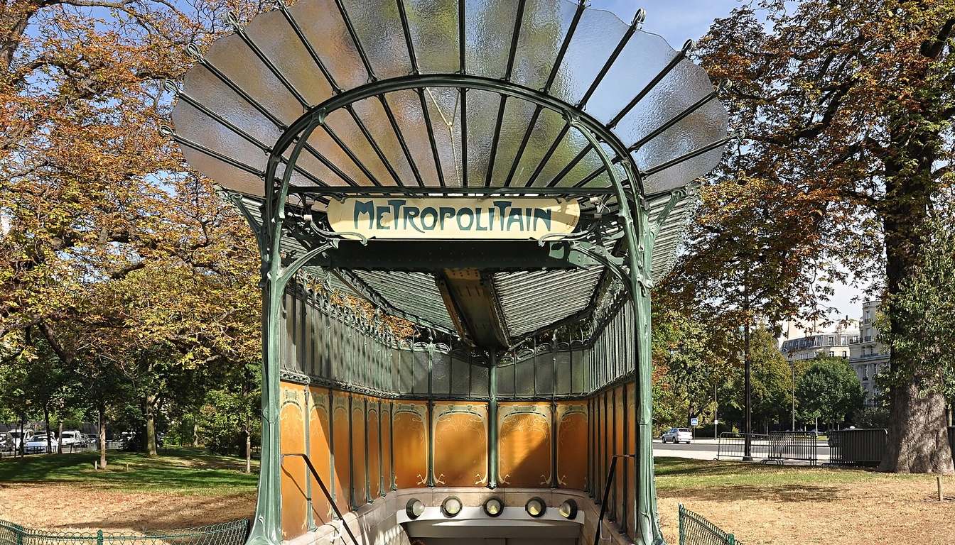 Glass-canopied Guimard Art Nouveau Métro entrance at Porte Dauphine, green ironwork and amber panels amid autumn trees