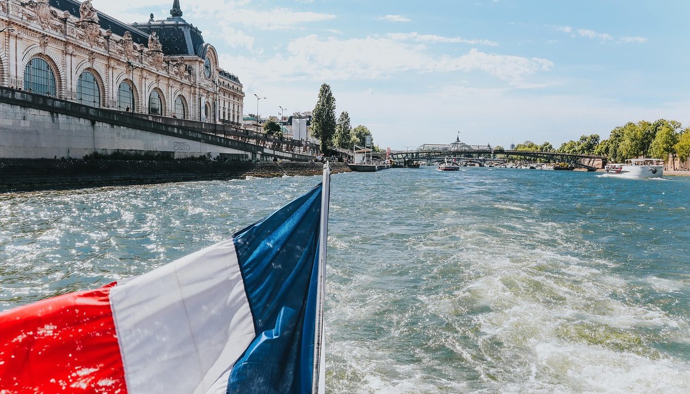 French flag on the stern of a cruise boat sailing the Seine past the Musée d'Orsay on a sunny day