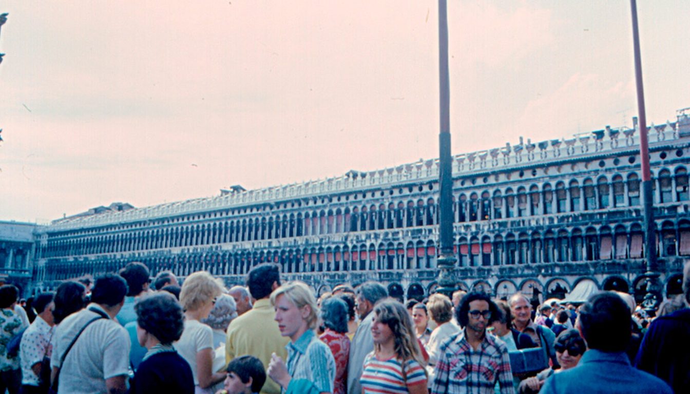 Dense crowd of tourists in St Mark's Square, Venice, in front of the arcaded Procuratie buildings