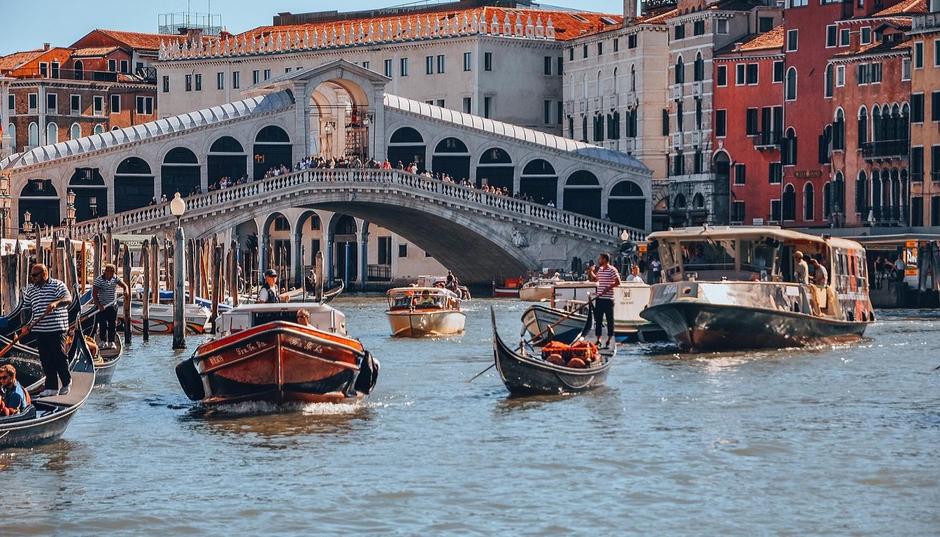 Rialto Bridge lined with people above the Grand Canal busy with gondolas and motorboats